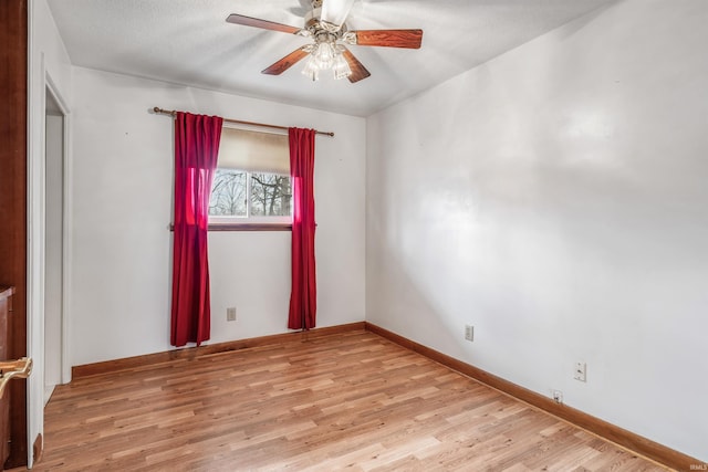 empty room with ceiling fan, light wood-style flooring, and baseboards