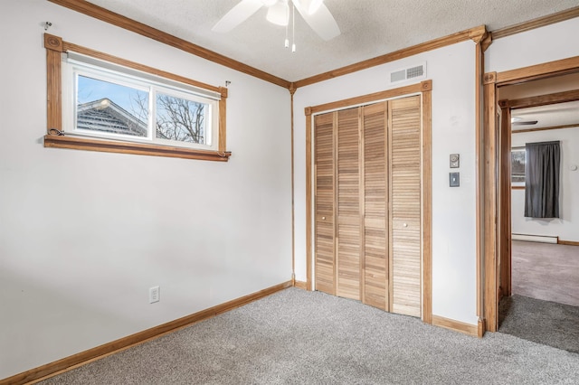 unfurnished bedroom with a textured ceiling, visible vents, baseboard heating, carpet, and crown molding