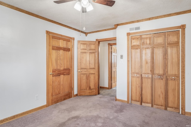 unfurnished bedroom featuring a textured ceiling, light carpet, visible vents, baseboards, and ornamental molding