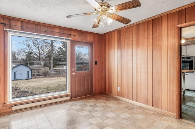 entrance foyer featuring light floors, a baseboard heating unit, ceiling fan, wooden walls, and a textured ceiling