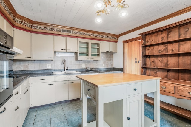 kitchen with crown molding, open shelves, backsplash, a sink, and tile patterned floors