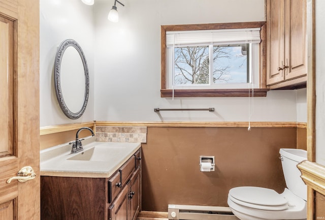 half bath featuring a baseboard heating unit, vanity, and toilet