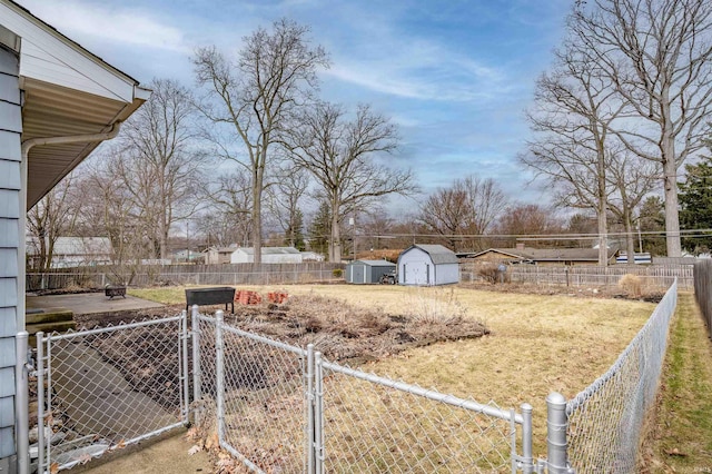 view of yard featuring a shed, an outdoor structure, a fenced backyard, and a gate