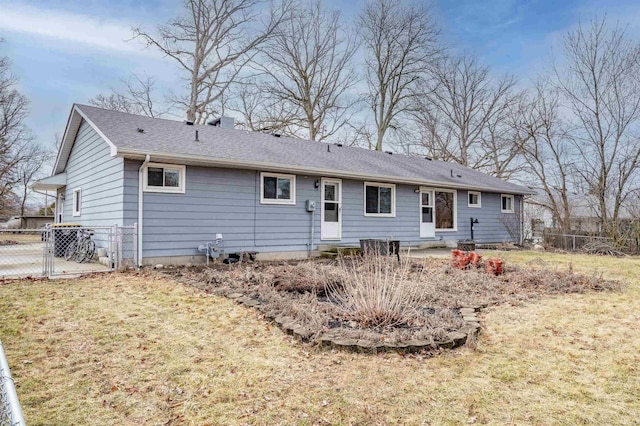 rear view of property featuring roof with shingles, a lawn, fence, and a gate