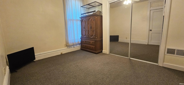 unfurnished bedroom featuring dark colored carpet, a closet, visible vents, ceiling fan, and baseboards