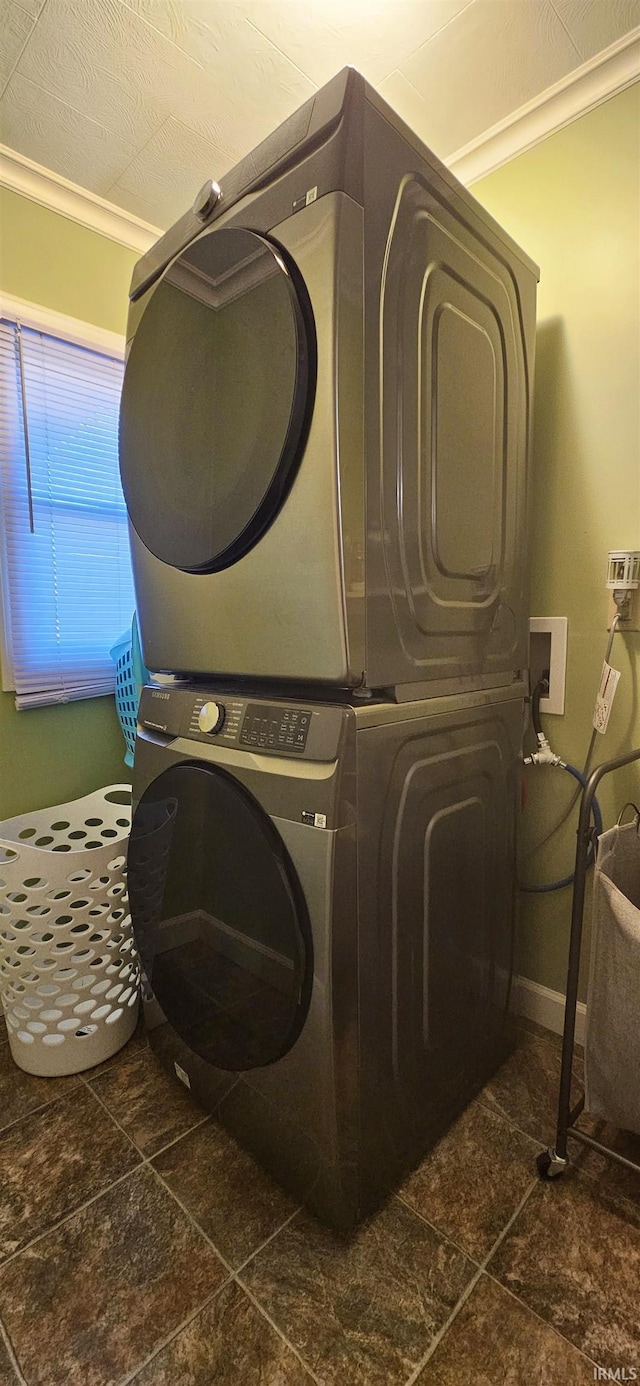 washroom with stacked washer and dryer, stone finish floor, and laundry area