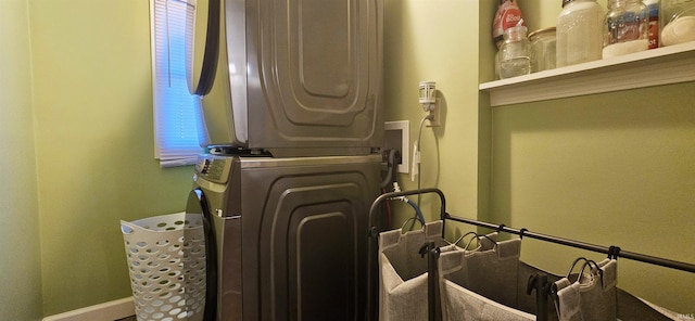 laundry area with laundry area, baseboards, and stacked washing maching and dryer