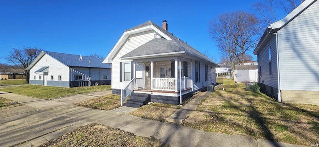 view of front of house featuring a porch, central AC, a shingled roof, and a front lawn