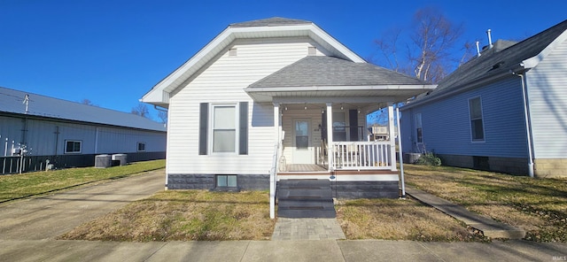 view of front of home with a porch, roof with shingles, central AC unit, and a front yard