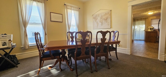 carpeted dining room with tile patterned flooring and baseboards