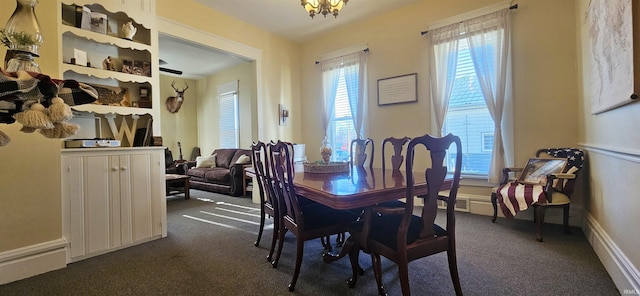 dining area with an inviting chandelier, baseboards, and dark carpet