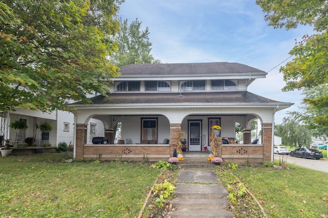 view of front of house featuring a porch, a front yard, and brick siding