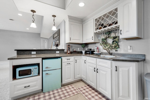 kitchen with white microwave, a sink, white cabinets, fridge, and dark countertops