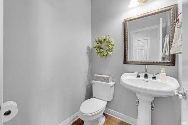 half bath with wood finished floors, toilet, and baseboards