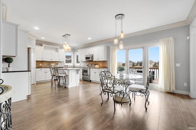 dining room featuring baseboards, ornamental molding, light wood-type flooring, and recessed lighting