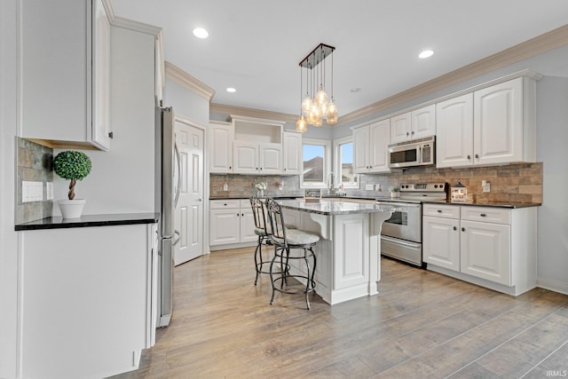 kitchen featuring stainless steel appliances, white cabinets, a sink, and a kitchen breakfast bar