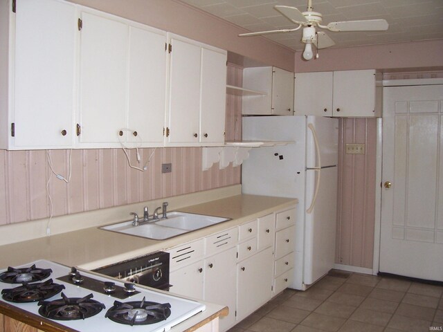 kitchen with light countertops, a sink, freestanding refrigerator, and white cabinetry