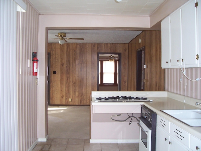 kitchen with white appliances, light countertops, a sink, and wooden walls