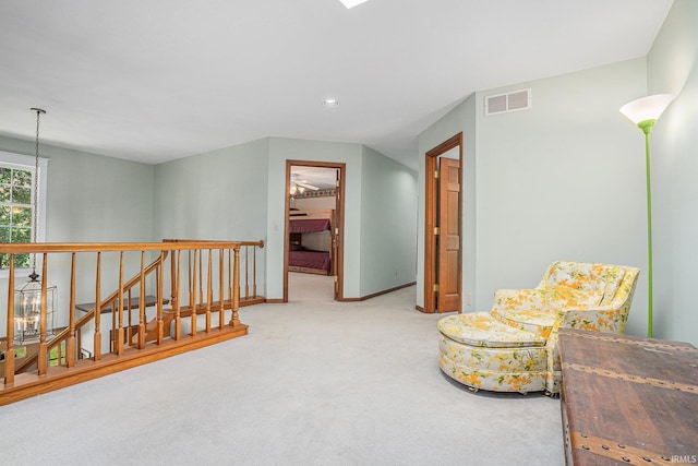 sitting room featuring baseboards, visible vents, an upstairs landing, carpet floors, and a notable chandelier