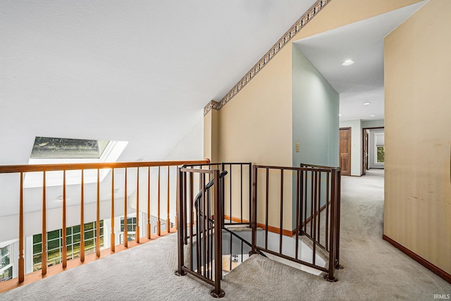 corridor with recessed lighting, a skylight, carpet, and an upstairs landing