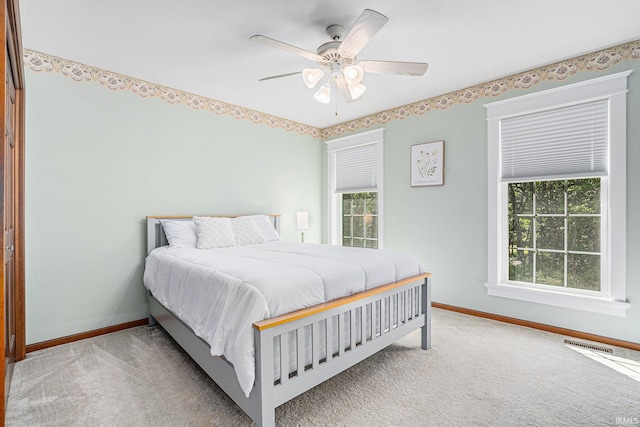 carpeted bedroom featuring ceiling fan, visible vents, and baseboards