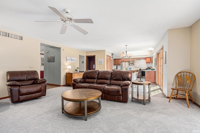 living room featuring light colored carpet, visible vents, baseboards, and ceiling fan with notable chandelier