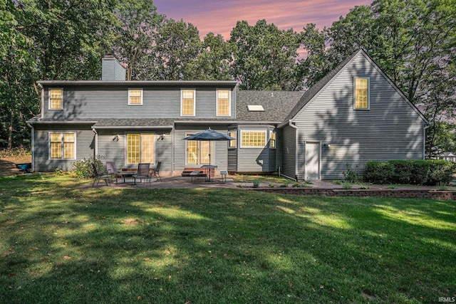 rear view of property with a yard, a chimney, and a patio