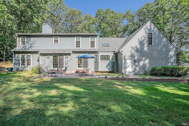 rear view of property with a yard, a chimney, and a patio area