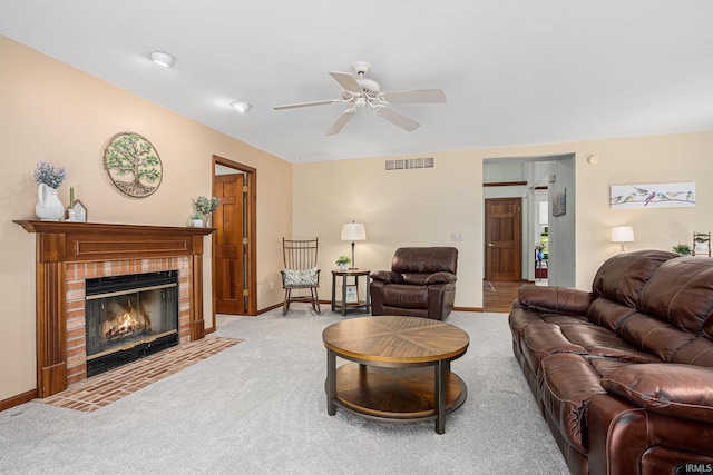 carpeted living room featuring baseboards, a fireplace, visible vents, and ceiling fan