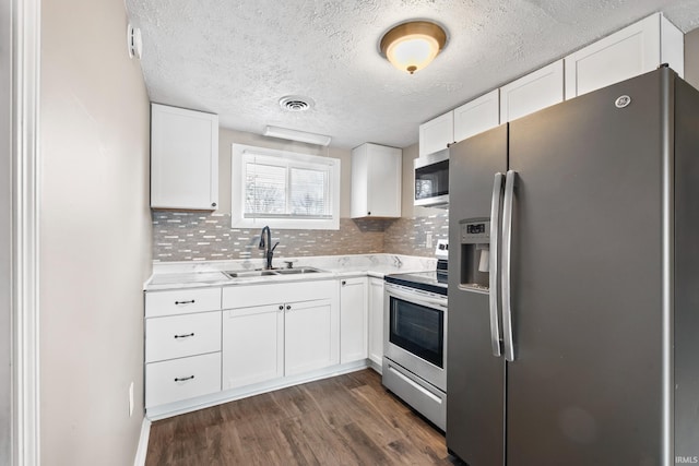 kitchen featuring dark wood-style floors, stainless steel appliances, light countertops, visible vents, and a sink