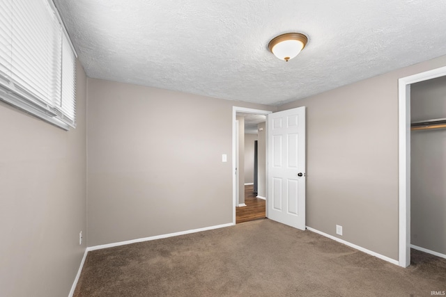 unfurnished bedroom featuring carpet floors, a closet, a textured ceiling, and baseboards