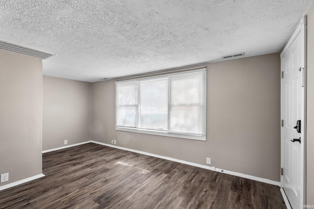 spare room with visible vents, a textured ceiling, baseboards, and wood finished floors