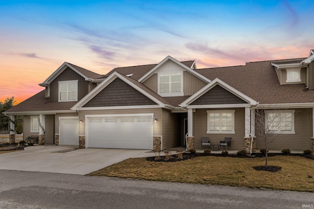 craftsman-style home featuring driveway, stone siding, an attached garage, and a yard