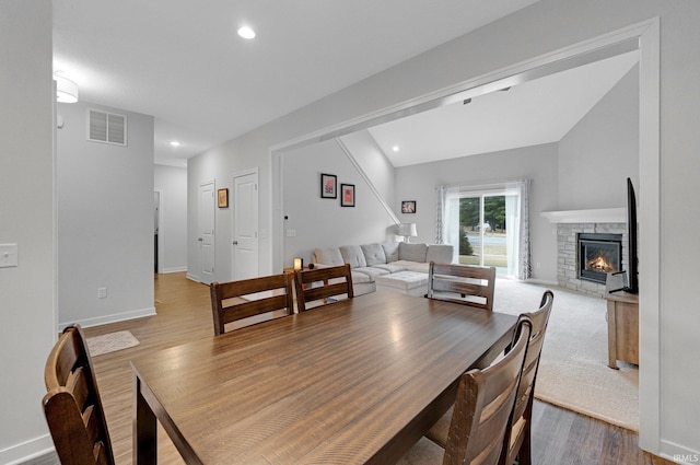 dining area featuring recessed lighting, visible vents, wood finished floors, and a stone fireplace