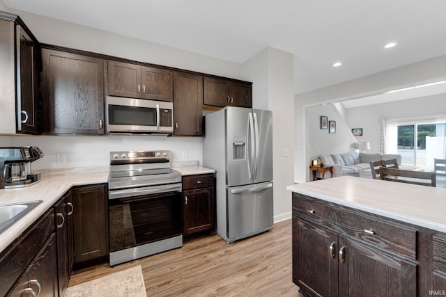 kitchen with recessed lighting, light wood-style floors, dark brown cabinets, appliances with stainless steel finishes, and light countertops