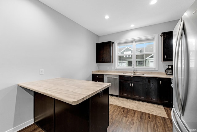 kitchen with dark wood-style flooring, light countertops, appliances with stainless steel finishes, a sink, and a peninsula