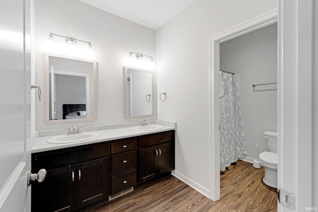 full bath featuring double vanity, wood finished floors, a sink, and toilet