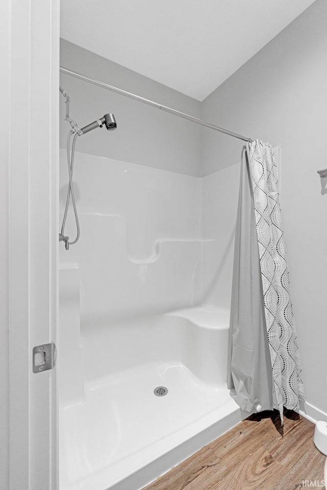 bathroom with curtained shower and wood finished floors