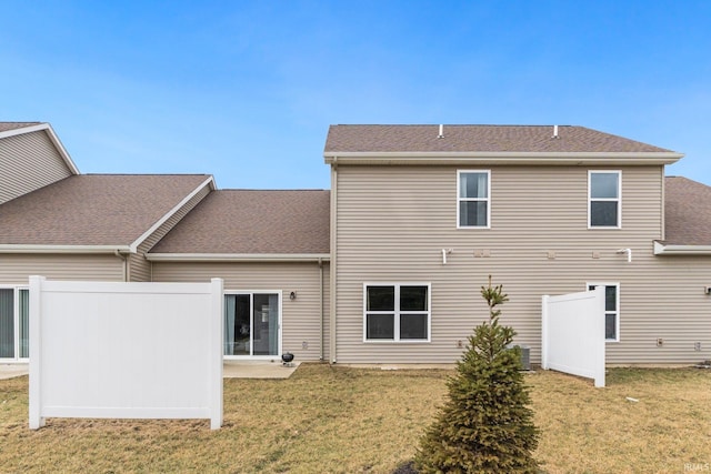 rear view of property with roof with shingles and a lawn