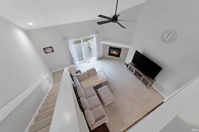 living room featuring a stone fireplace, a ceiling fan, baseboards, stairway, and carpet