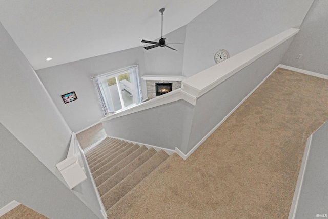 staircase with a ceiling fan, carpet, a glass covered fireplace, and baseboards