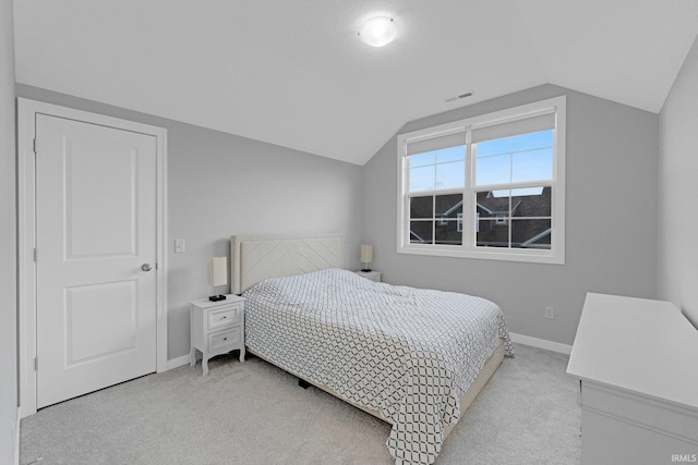 carpeted bedroom featuring vaulted ceiling, visible vents, and baseboards