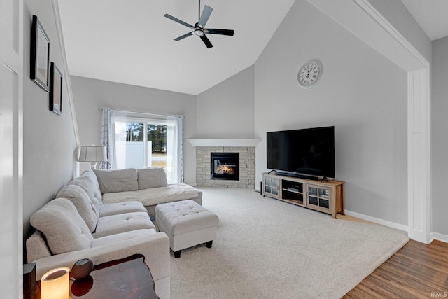 living room with baseboards, ceiling fan, wood finished floors, a fireplace, and high vaulted ceiling