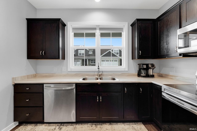 kitchen with stainless steel appliances, a sink, light countertops, and dark brown cabinetry