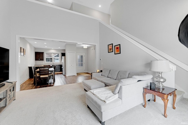 living room featuring recessed lighting, a towering ceiling, and wood finished floors