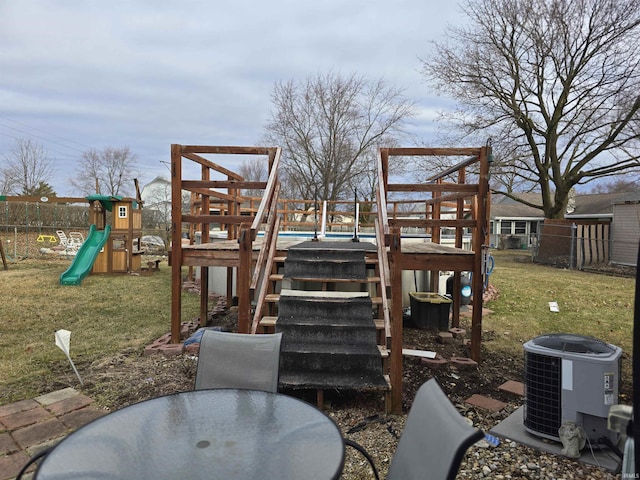 view of jungle gym featuring central air condition unit, outdoor dining space, fence, and a yard