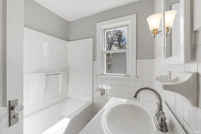 bathroom with a sink, tile walls, and shower / bathtub combination