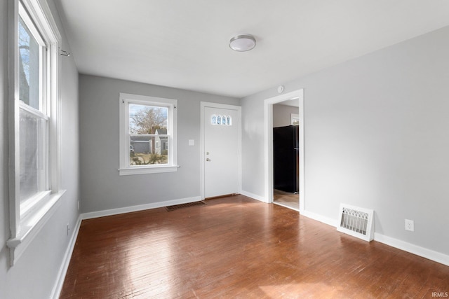 spare room with wood-type flooring, visible vents, and baseboards