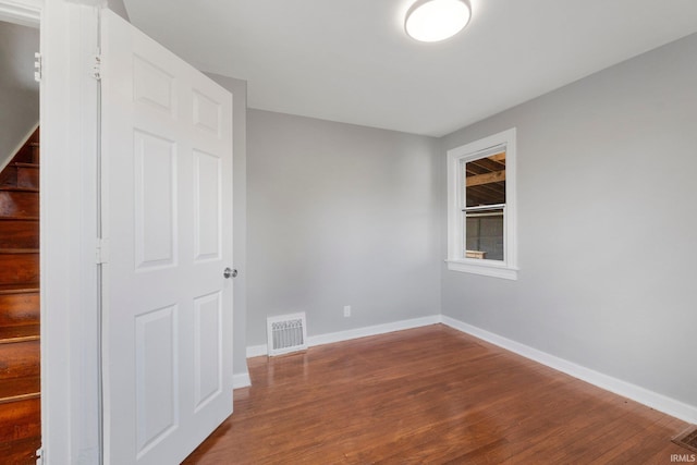 spare room with baseboards, stairs, visible vents, and wood finished floors