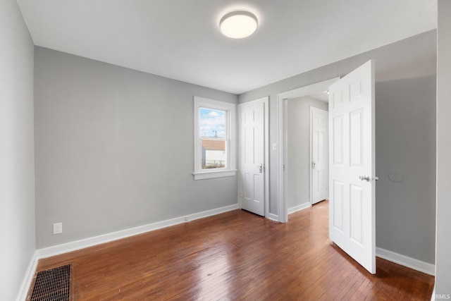 unfurnished bedroom featuring baseboards, visible vents, and hardwood / wood-style floors